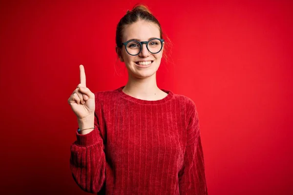 Młoda Piękna Ruda Kobieta Ubrana Luźny Sweter Odizolowanym Czerwonym Tle — Zdjęcie stockowe