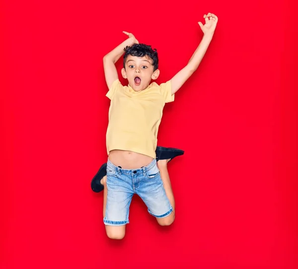 Adorable Niño Con Ropa Casual Saltando Sobre Fondo Rojo Aislado — Foto de Stock