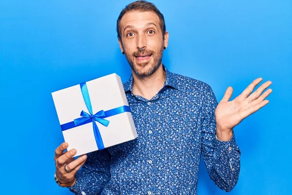 Jovem Homem Bonito Segurando Presente Celebrando Realização Com Sorriso Feliz — Fotografia de Stock