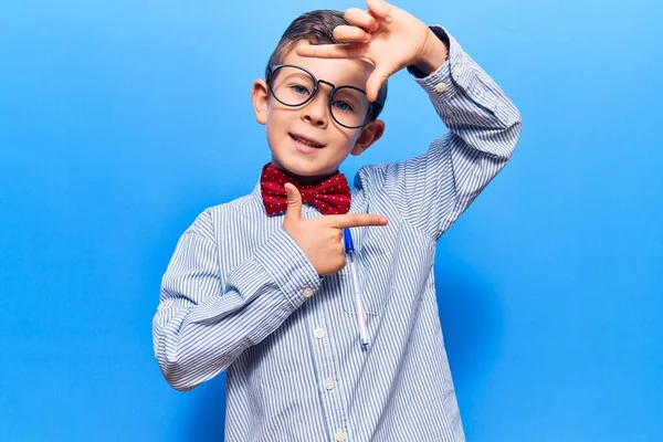 オタクの弓タイとメガネを身に着けているかわいいブロンドの子供は幸せな顔で手や指でフレームを作り笑顔 創造性と写真の概念 — ストック写真