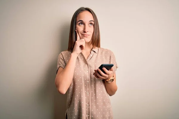 Young beautiful woman having conversation using smartphone looking at the mobile serious face thinking about question, very confused idea