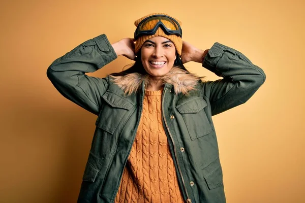 冬の天候のためのスキーグラスとコートを身に着けている若い美しいパニック女性リラックスしてストレッチ 腕と頭と首の後ろの手は幸せな笑顔 — ストック写真