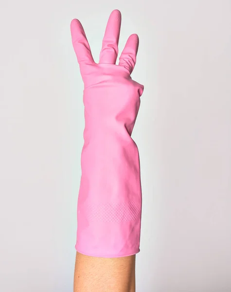 ピンクのクリーニング手袋を身に着けている白人の若い女性の手 孤立した白い背景の上に指が3番を行う表示 — ストック写真