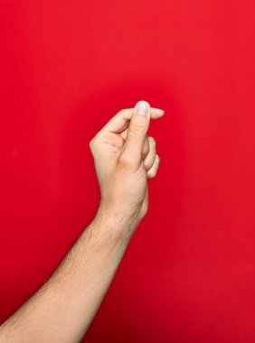 Güzel bir el, parmaklarını kaldırmış, izole edilmiş kırmızı arka planda para işareti yapıyor.