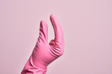 İzole edilmiş pembe arka plan üzerinde temizlik eldiveni olan beyaz bir adamın eli. Görünmez bir şeyi alıp, parmaklarında boşluk gösteren bir nesneyi tutuyor.