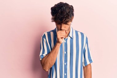 Günlük kıyafetler giyen genç İspanyol adam kendini iyi hissetmiyor ve soğuk algınlığı veya bronşitin belirtisi olarak öksürüyor. sağlık hizmeti kavramı. 