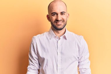 Yakışıklı, kel bir adam zarif bir gömlek giyiyor ve yüzünde mutlu ve havalı bir gülümseme var. şanslı kişi. 