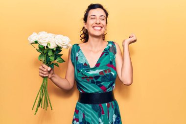 Çiçekleri tutan güzel İspanyol bir kadın gururla bağırıyor, zaferi kutluyor ve başarıyı kollarını kaldırarak kutluyor. 