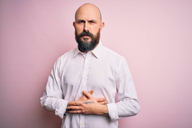 Sakallı yakışıklı, zarif gömlekli, soyutlanmış, pembe arka planda, midesi üstünde, midesi ağrıyan, hazımsızlık çeken, ağrılı bir hastalığa yakalanmış bir adam. Ache kavramı.
