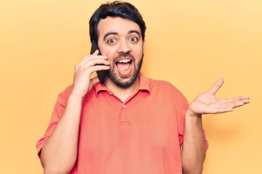 Genç İspanyol bir adam akıllı telefonda konuşuyor başarıyı mutlu bir gülümsemeyle kutluyor ve kazanan el kaldırarak ifade ediyor. 