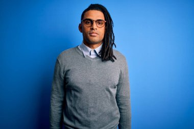 Rastgele kazak giyen ve yüzünde ciddi bir ifade olan gözlüklü Afro-Amerikan genç adam. Basit ve doğal bir şekilde kameraya bakıyorsun..