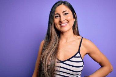 Genç, güzel bir kadın, mor izole edilmiş arka planda, yaz çizgili, mutlu ve serin bir gülümseme takınıyor. Şanslı kişi..