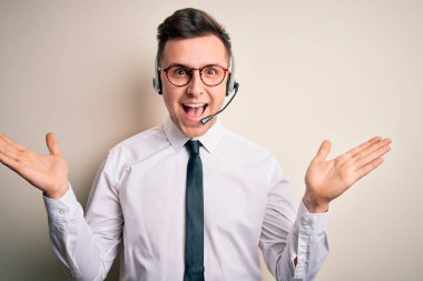 Müşteri hizmetlerinde çağrı merkezi kulaklığı takan yakışıklı beyaz bir iş adamı çılgın kutlamalar yapıyor ve kollarını kaldırıp heyecanla haykırarak başarıya hayret ediyor. Kazanan konsept