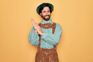 Almanya festivali için geleneksel Alman Ekim Festivali kıyafeti giyen genç yakışıklı adam alkışlıyor ve alkışlıyor mutlu ve neşeli, gururlu elleri bir arada