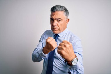 Orta yaşlı, yakışıklı, gri saçlı, şık gömlekli ve kravatlı bir iş adamı. Yumruk savunma hareketleriyle dövüşmeye hazır, kızgın ve üzgün yüzlü, sorundan korkan.