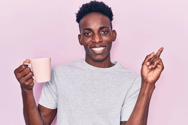 Mladý Africký Američan Drží Kávu Úsměvem Šťastný Ukazující Rukou Prstem — Stock fotografie
