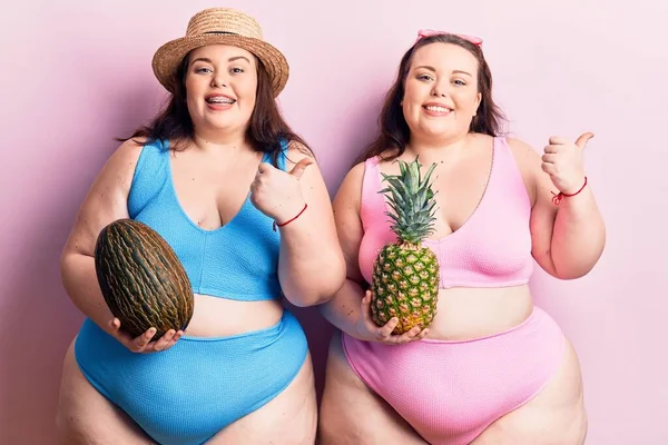 Młode Bliźniaczki Size Bikini Trzymające Melona Ananasa Kciukiem Góry Uśmiechnięte — Zdjęcie stockowe