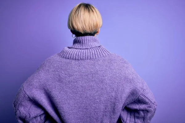 겨울에 머리에 터틀넥 스웨터를 금발의 여자가 보라색 위에서 거꾸로 바라보고 — 스톡 사진