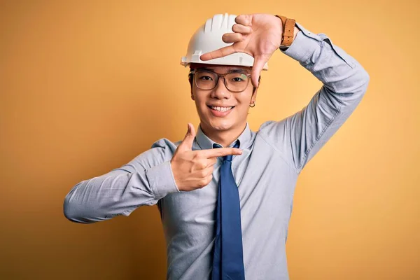 年轻英俊的中国建筑师 戴着安全帽 打着黄底领带 面带微笑 手指手画脚 笑容满面 创意和摄影概念 — 图库照片