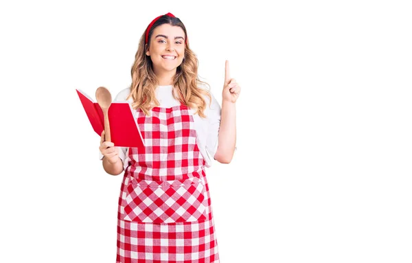 Una Joven Caucásica Que Lleva Delantal Sosteniendo Libro Recetas Cuchara — Foto de Stock