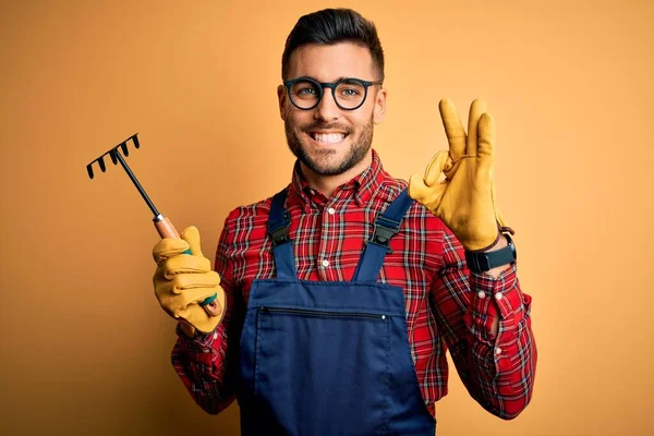 Junger Gärtner Trägt Arbeitsschürze Mit Handschuhen Und Werkzeug Über Gelbem — Stockfoto