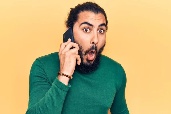 スマートフォンで話している会話をしている若いアラブ人男性が怖がっていると驚きのために口を開けて驚いて 不信の顔 — ストック写真