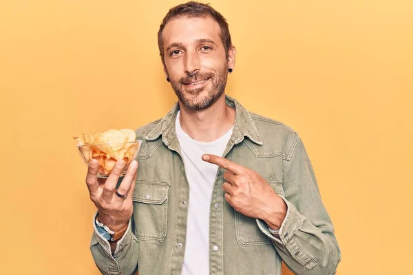 Jovem Homem Bonito Segurando Batata Frita Sorrindo Feliz Apontando Com — Fotografia de Stock