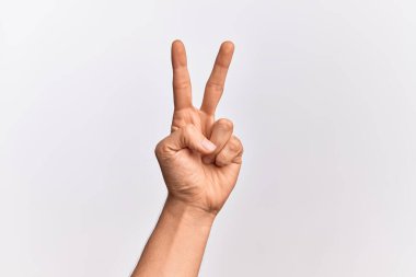 Beyaz arka planda parmaklarını gösteren beyaz tenli bir gencin eli iki parmağını gösteriyor, işaret ediyor zafer ve kazanan sembol.