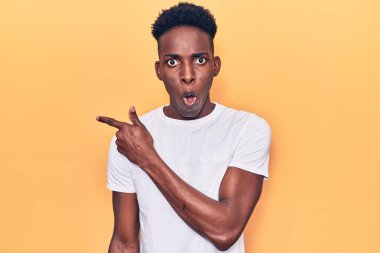 Gündelik giysiler giyen Afro-Amerikan genç adam parmaklarını yana çevirerek şaşırdı, ağzı açık hayret içinde kaldı.. 