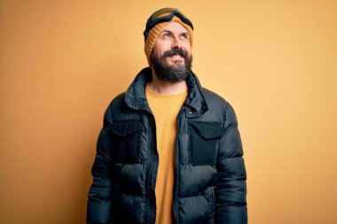 Sakallı, kar maskesi takmış, kar maskesi takmış, kar maskesi takmış, yüzünde gülümseme, doğal bir ifade olan yakışıklı kayakçı. Kendinden emin gülen.