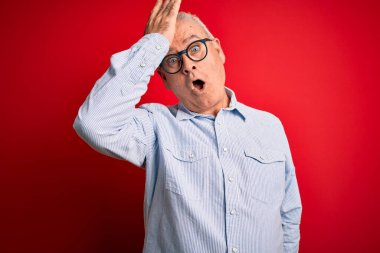 Orta yaşlı, beyaz, sıradan çizgili tişört giyen ve kırmızı arka planda gözlük takan yakışıklı bir adam. Hatayla el ele tutuşurken şaşırmış. Hatayı hatırla. Unuttum, kötü hafıza konsepti.