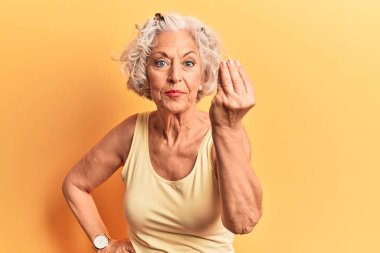 Yaşlı, gri saçlı, günlük kıyafetler giyen, italyan jestleri yapan, elleri ve parmakları kendine güvenen bir kadın. 