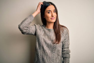 Genç, güzel, esmer kadın izole edilmiş beyaz arka plan üzerine gündelik kazak giyip soru sormayı merak ediyor. Şüpheyle kararsız, kafa kafaya düşünerek. Düşünceli kavram.