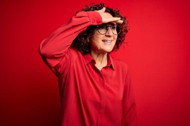 Orta yaşlı, kıvırcık saçlı, rahat gömlekli, kırmızı arka planda gözlüklü çok mutlu ve tebessüm eden güzel bir kadın. Konsept aranıyor.