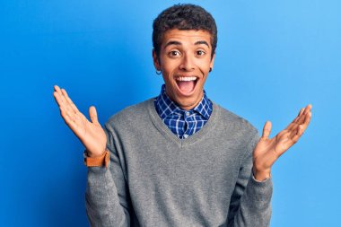 Genç Afrikalı Amerikalı günlük giysiler giymiş mutlu bir gülümsemeyle zaferi kutlayan ve ellerini kaldırarak kazanan bir ifade takınıyor. 