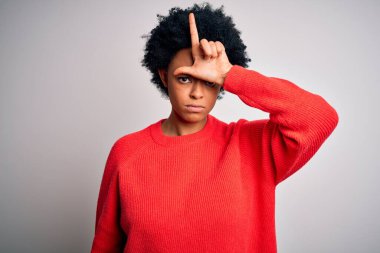 Kıvırcık saçlı, kırmızı süveter giyen, alnında parmakları olan insanlarla alay eden, ezik jestler yapan, alay eden güzel Afro-Amerikan bir kadın..