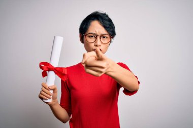 Üniversiteden mezun olmuş, gözlüklü, güzel Çinli bir öğrenci, diplomasını kameraya işaret ederek aldı. Ve sen, el işareti, ön taraftan pozitif ve kendinden emin bir hareket.