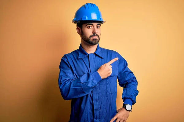 Mechanische Man Met Baard Blauw Uniform Veiligheidshelm Gele Achtergrond Wijzend — Stockfoto