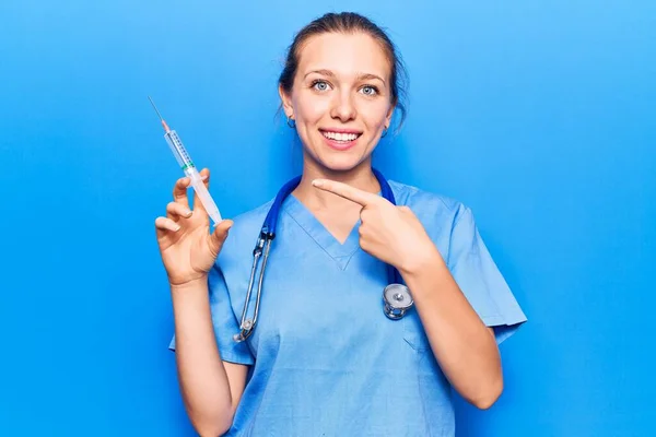 Doktor Üniforması Giyen Genç Sarışın Kadın Elinde Şırıngayla Gülümsüyor — Stok fotoğraf