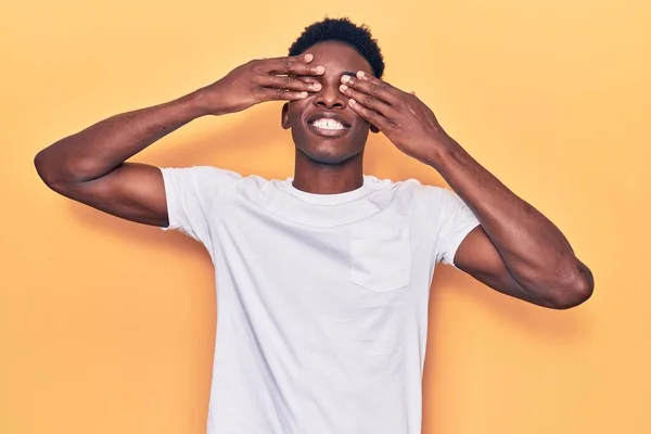 笑顔で陽気で面白い手で目を覆うカジュアルな服を着ている若いアフリカ系アメリカ人男性 視覚障害の概念 — ストック写真
