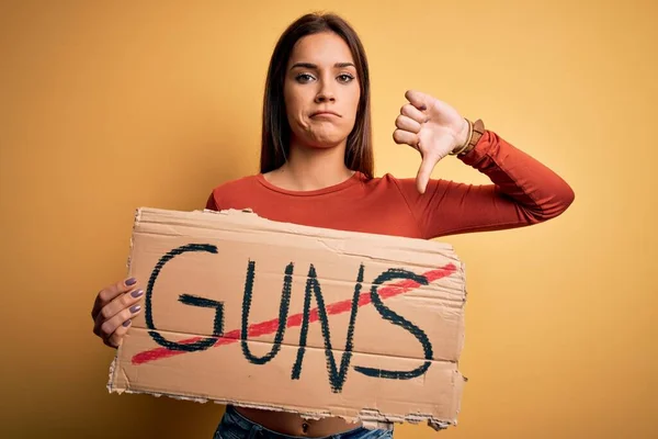 若い美しい活動家の女性は 怒りの顔を持つストップ銃のメッセージと平和保持バナーを求めて 親指で嫌いを示す負の記号を 拒否の概念 — ストック写真