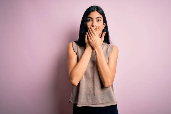 ピンクの背景にセーターを着た若い美しいヒスパニック系のファッション女性がミスのために手で口をカバーショックを受けました 秘密概念 — ストック写真