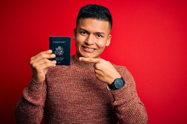 Genç, yakışıklı, Latin bir turist elinde Birleşik Devletler pasaportuyla elini ve parmağını göstererek mutlu mesut geziyor.