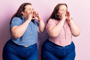 Genç ve cüsseli ikizler gündelik kıyafetler giyip elleri ağızlarının üstünde bağırarak bağırıyorlar. 