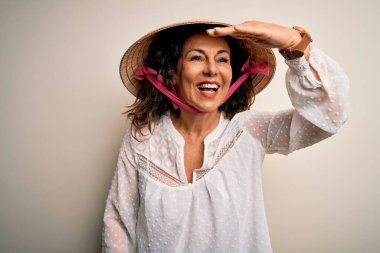 Orta yaşlı esmer kadın, beyaz arka planda Asyalı geleneksel konik şapka takıyor. Çok mutlu ve gülümsüyor. Konsept aranıyor.