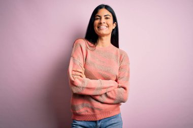 Moda kıyafetleri giyen genç ve güzel bir kadın. Manken, sokak tarzı giyiniyor. Pembe arka planda dikiliyor.