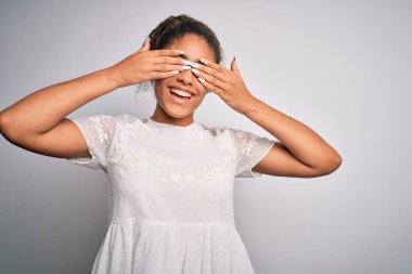 Genç, güzel, Afro-Amerikalı bir kız günlük tişört giyiyor beyaz arka plan üzerinde duruyor gözleri kapıyor ve neşeli ve komik gülümsüyor. Kör kavram.