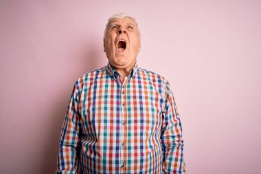 Üst düzey yakışıklı beyaz adam, pembe arka plan üzerine gündelik bir tişört giyip öfkeli ve sinirli çığlıklar atıyor, öfkeyle bağırıyor. Öfke ve agresif kavram.