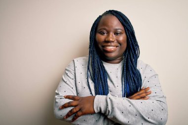 Beyaz arka planda kollarını kavuşturup kameraya bakarken gülümseyen, örgü ören Afro-Amerikan kadın. Pozitif kişi.