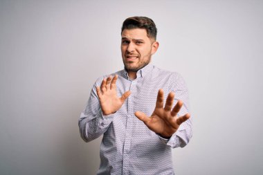 Mavi gözlü genç iş adamı, dışlanmış arka planda duran tiksindirici ifade, tiksindirici tepki yüzünden tiksinti ve korku dolu yüz ifadesi. Eller havada